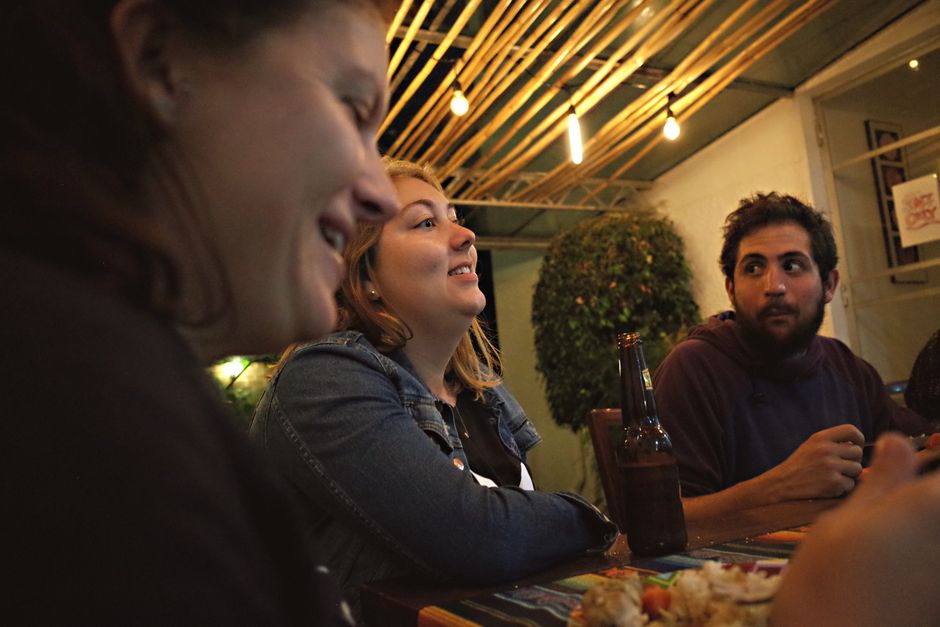 Three adults enjoying a casual meal together in a warmly lit indoor setting.